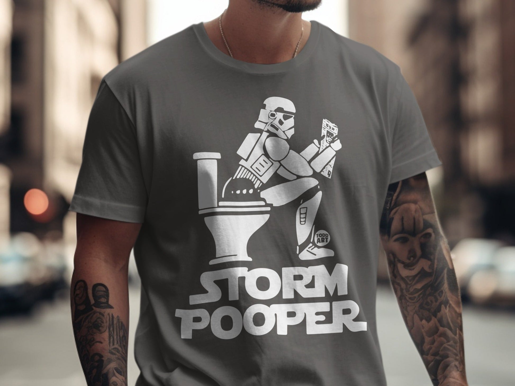 Stormtrooper sitting on a toilet, reading, on a t-shirt that says "Storm Pooper."
