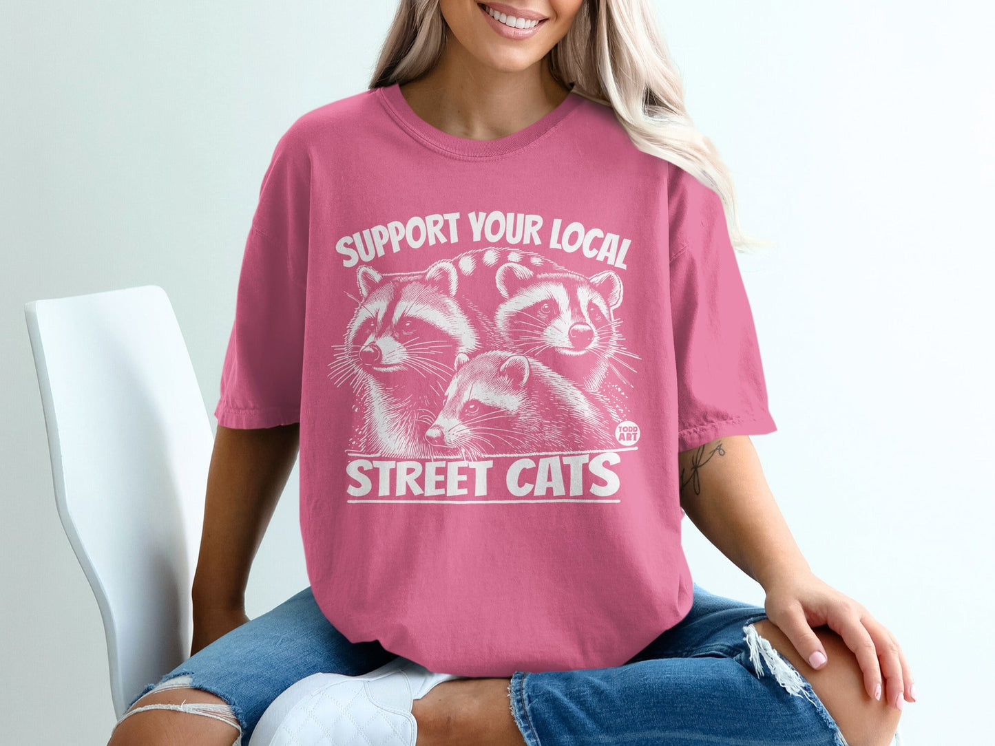 Pink t-shirt with three raccoons and "Support Your Local Street Cats" text.