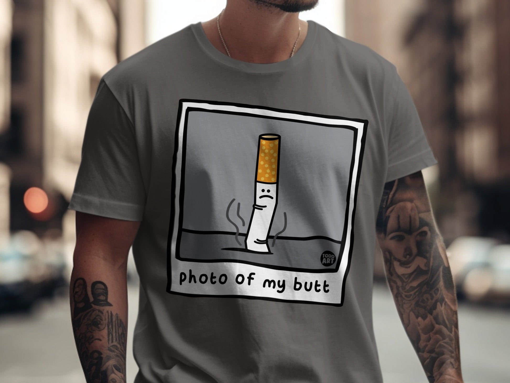 T-shirt featuring cartoon cigarette with sad face and text "photo of my butt".
