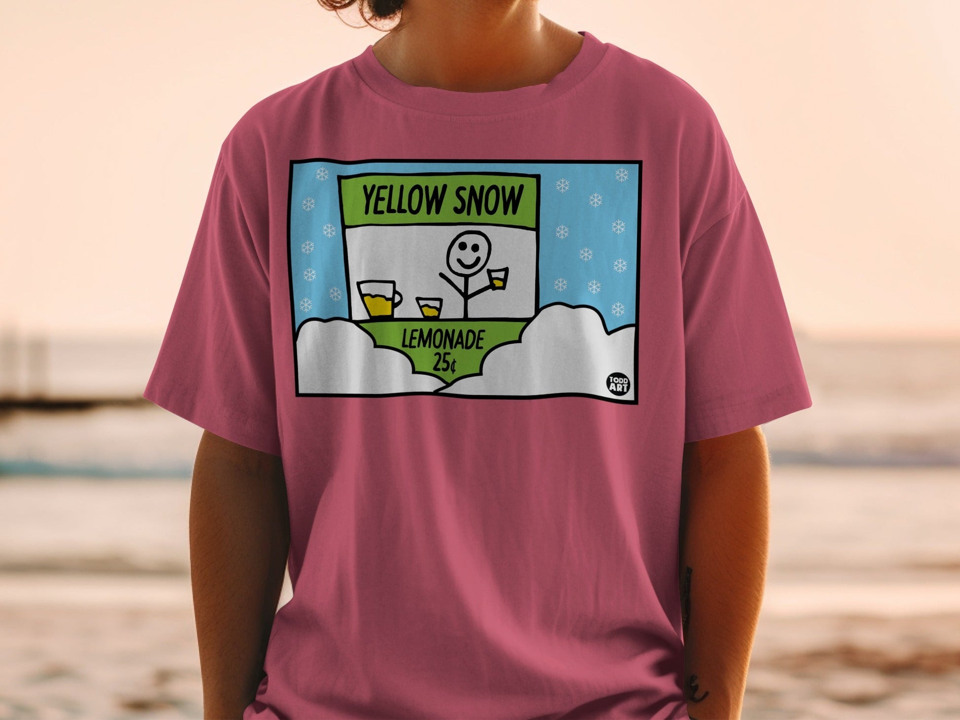 T-shirt graphic featuring "Yellow Snow Lemonade 25c" sign with a smiling snowman.