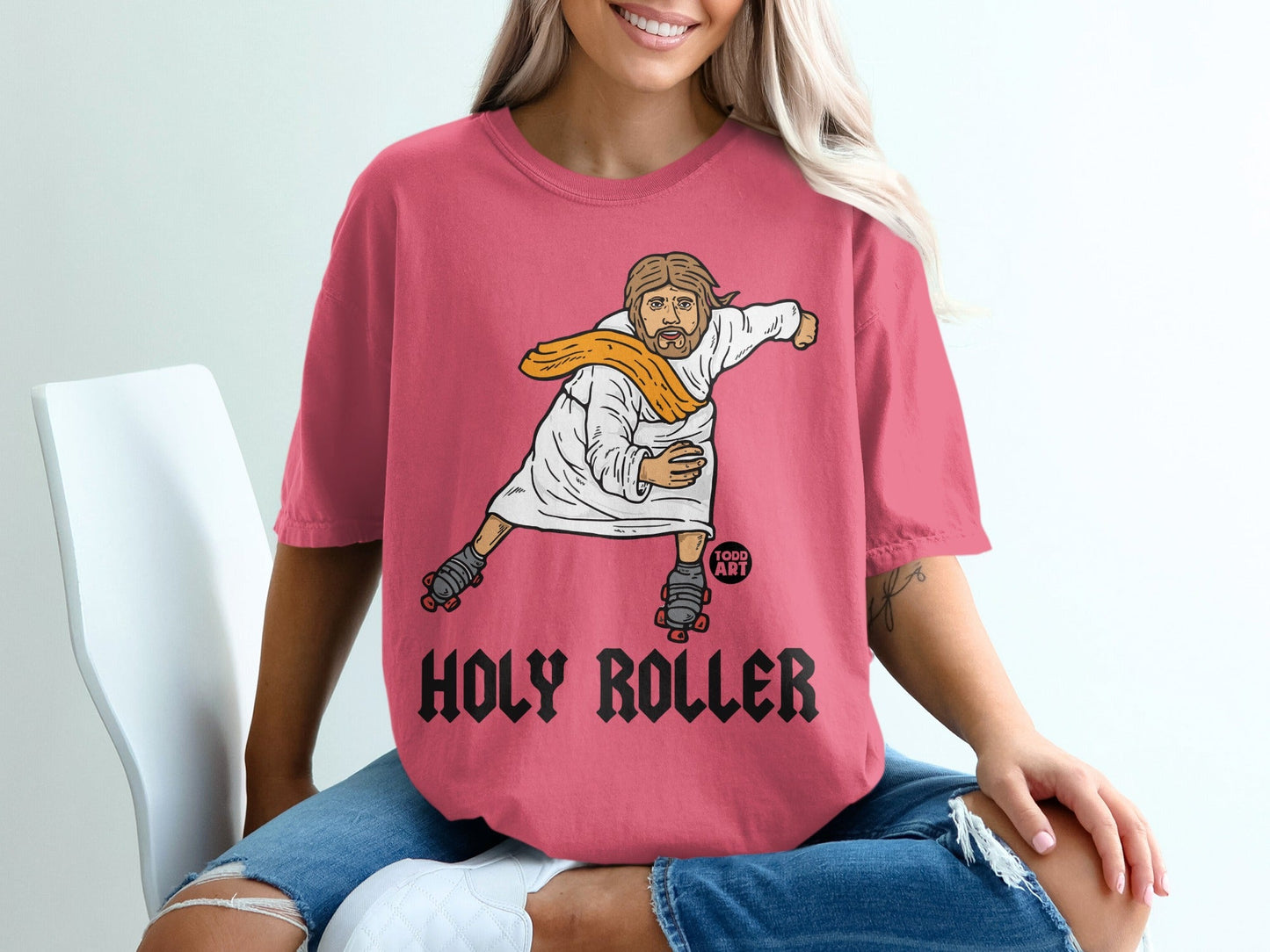 Jesus on roller skates wearing a white robe and orange sash, text reads "Holy Roller".