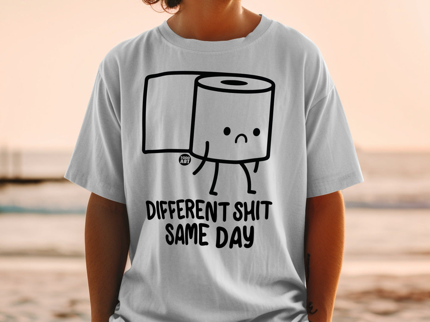 White t-shirt with cartoon toilet paper roll saying "DIFFERENT SHIT SAME DAY".