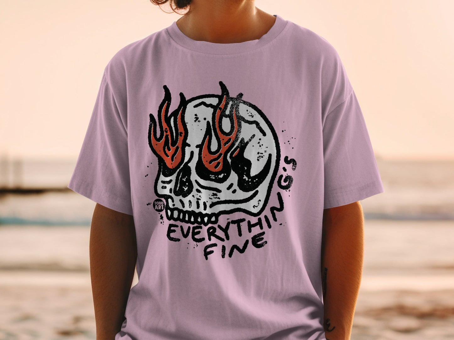 Skull with flames and "EVERYTHING FINE" text on a light purple t-shirt.