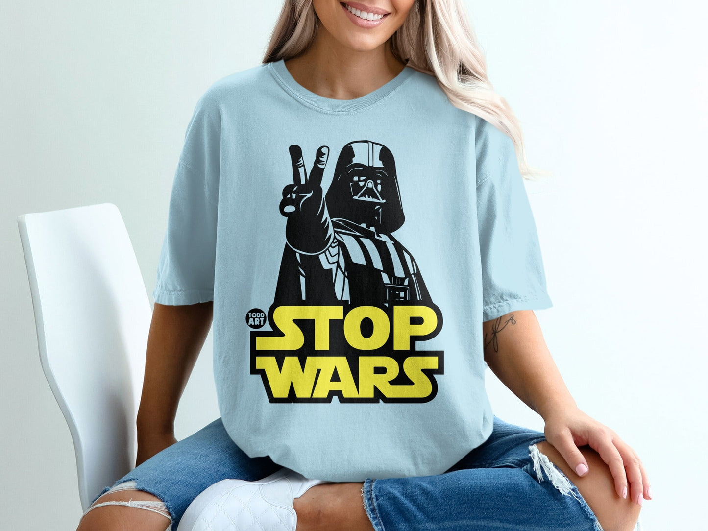 Darth Vader making peace sign over "STOP WARS" text on a light blue t-shirt.