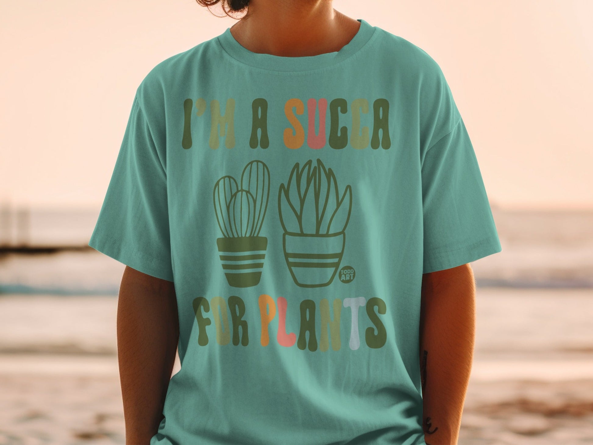 Teal t-shirt with cacti and succulents and text "I'm a succa for plants."