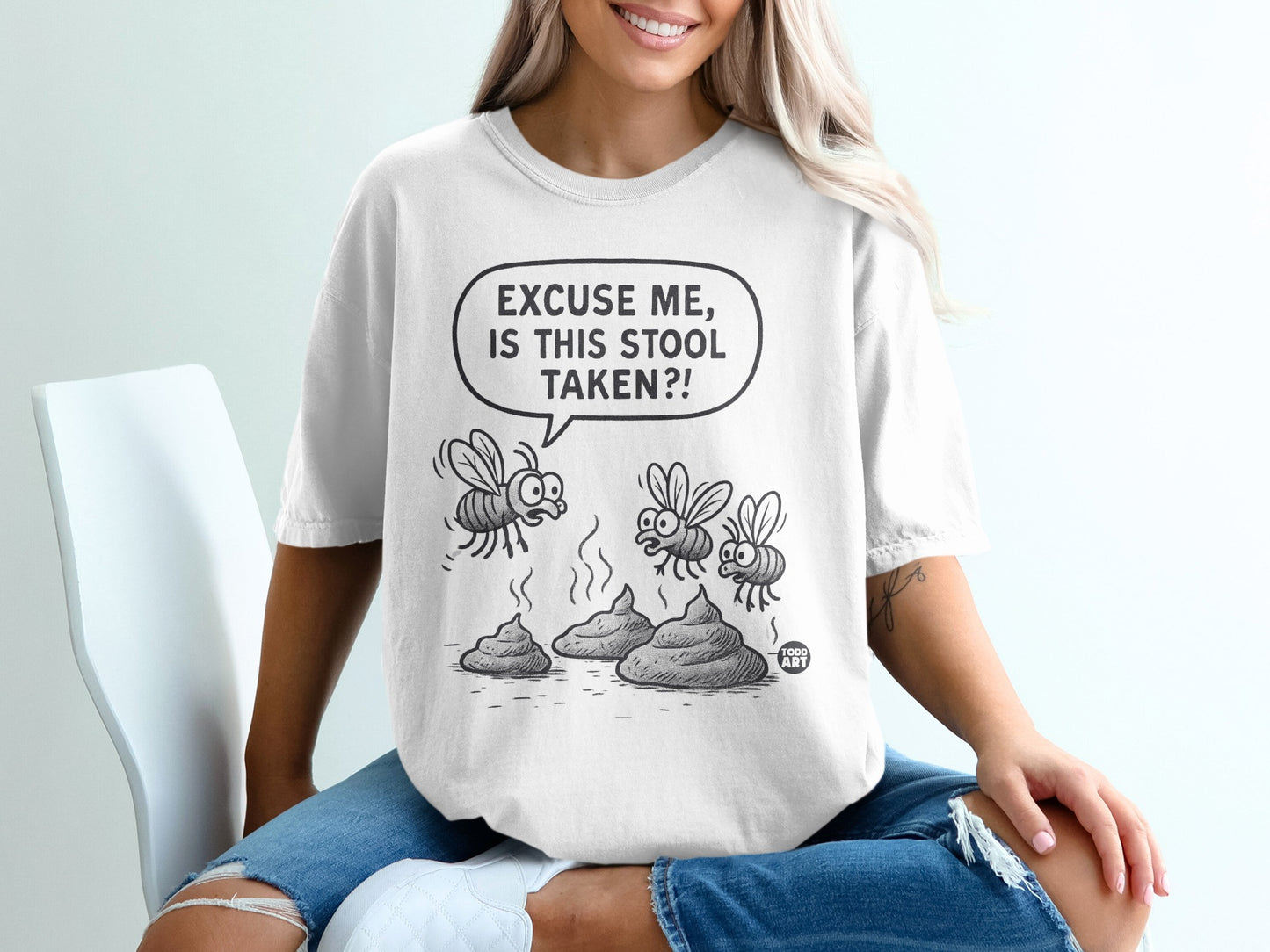 White t-shirt with cartoon flies hovering over three piles of poop, text reads "Excuse me, is this stool taken?!"