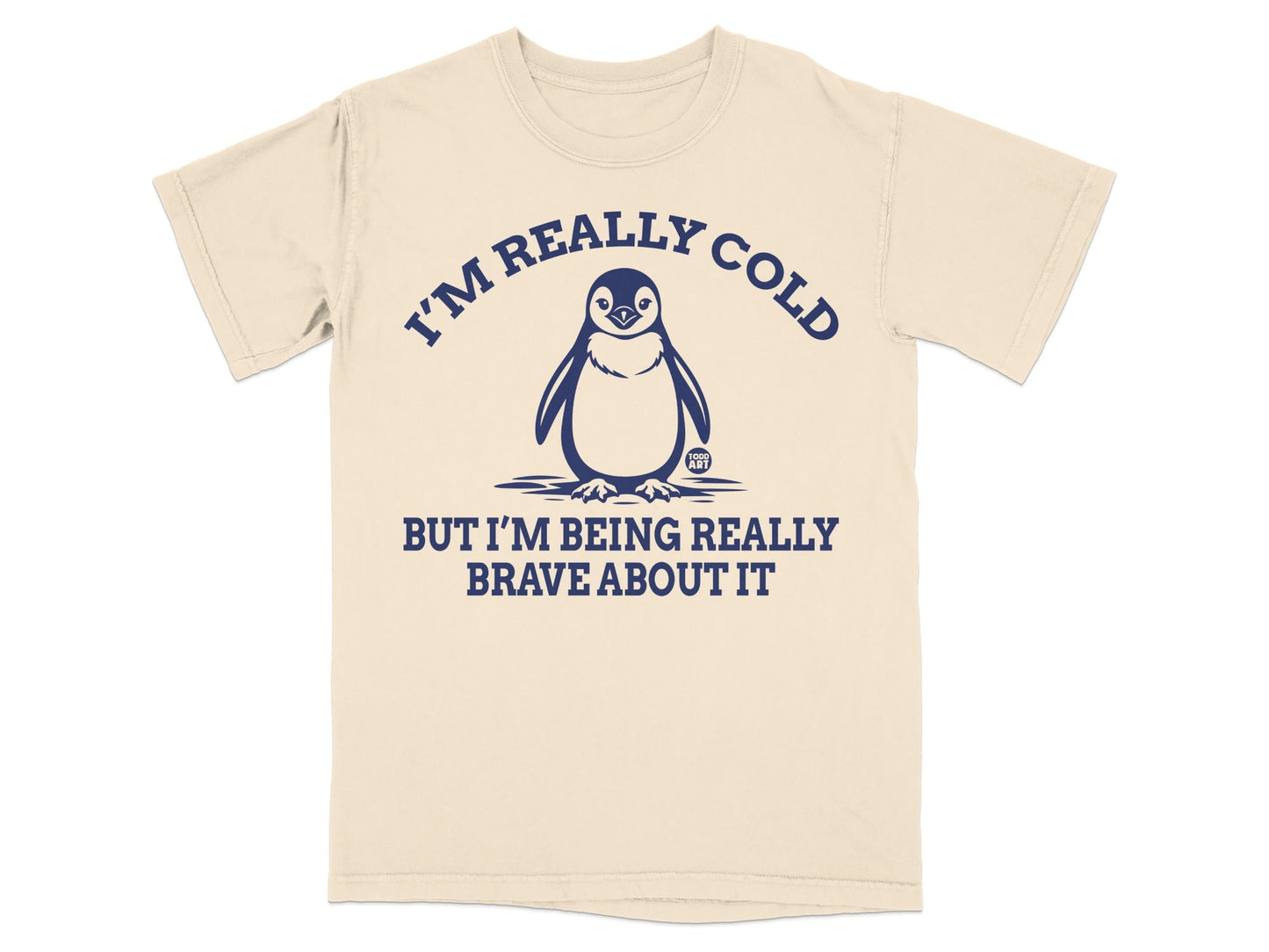 Beige t-shirt with a penguin graphic and text that reads "I'm really cold but I'm being really brave about it."