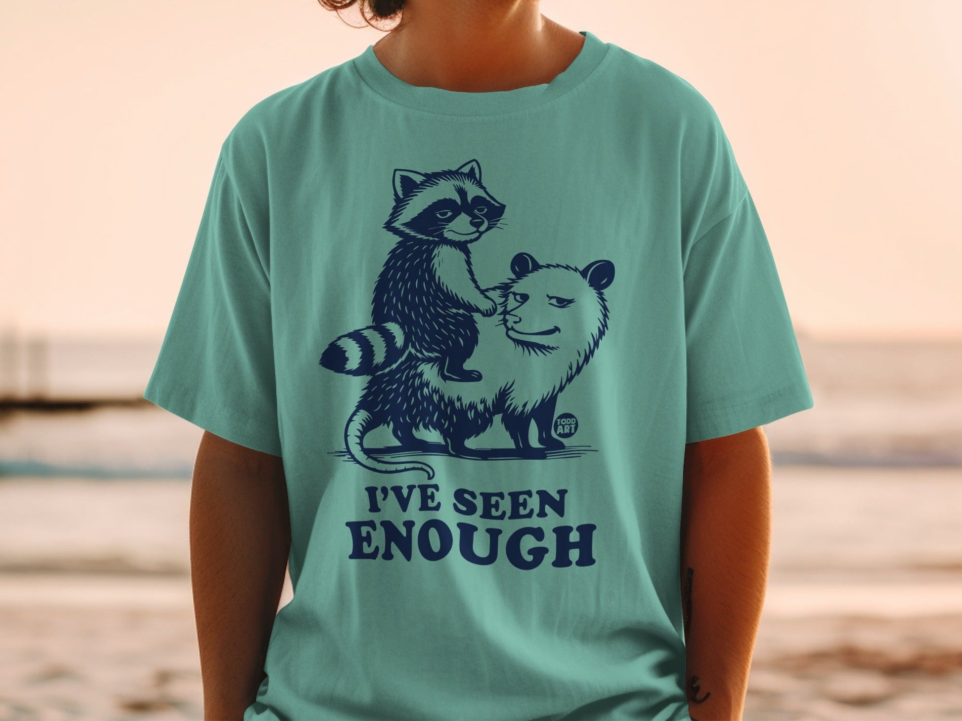 Teal t-shirt with raccoon riding a possum, text "I'VE SEEN ENOUGH".