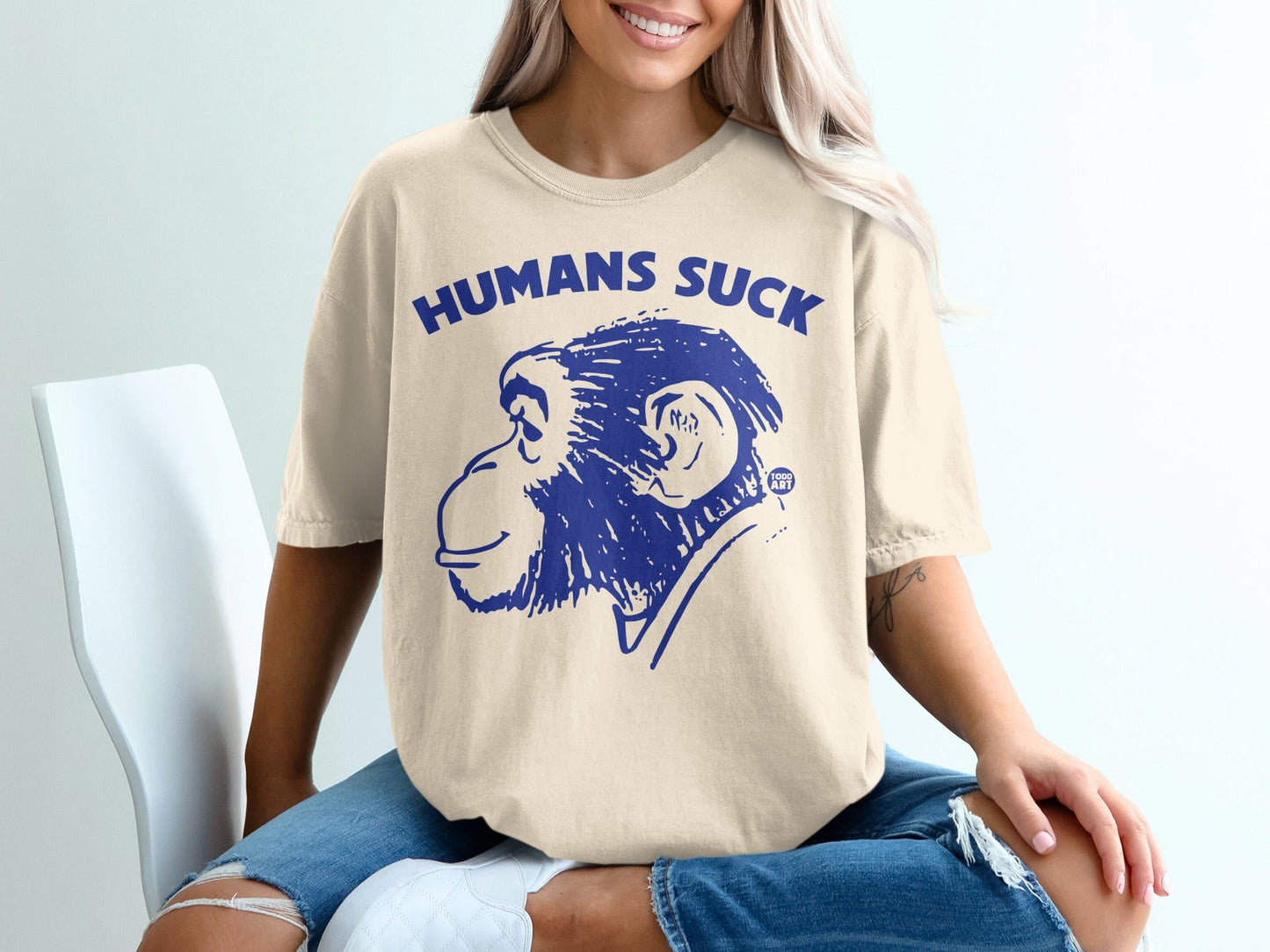 Cream t-shirt with blue "HUMANS SUCK" text and monkey graphic.
