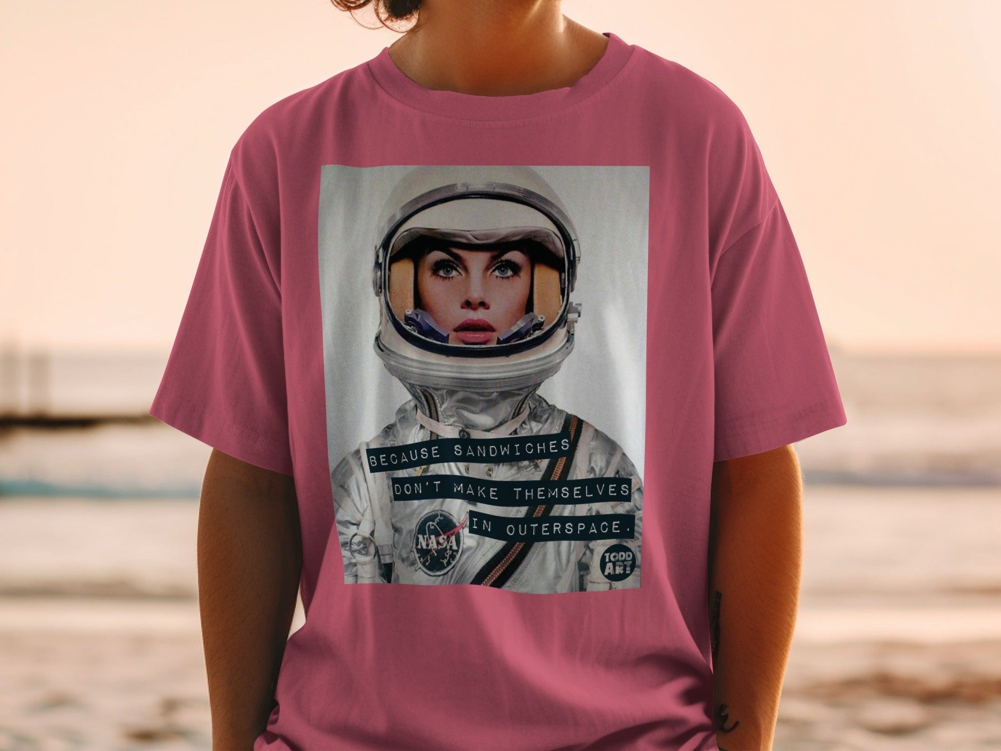 Woman in t-shirt featuring astronaut helmet graphic with text.