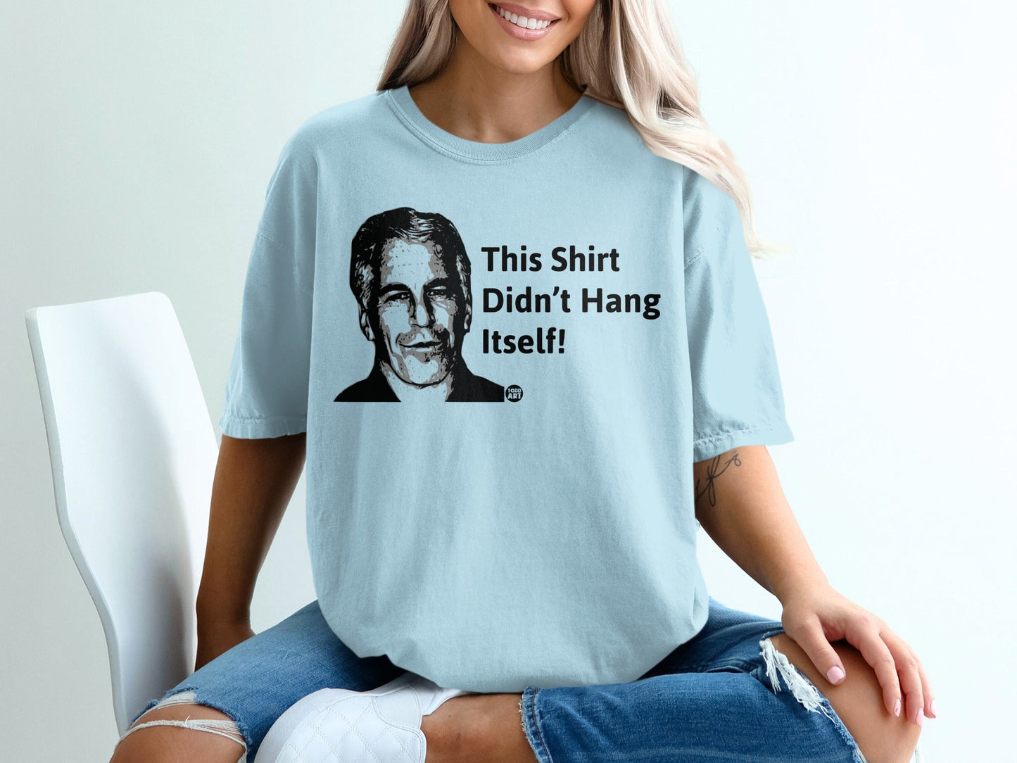 Light blue t-shirt with graphic of a man's face and text "This Shirt Didn't Hang Itself!".