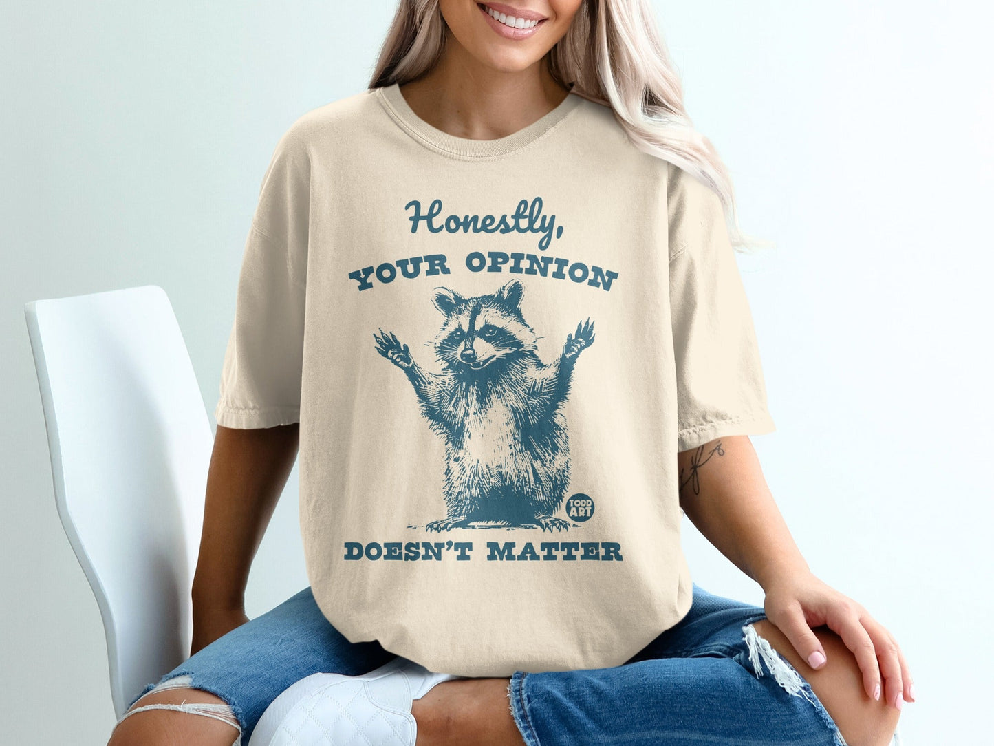 Cream t-shirt with raccoon graphic and text "Honestly, YOUR OPINION DOESN'T MATTER".