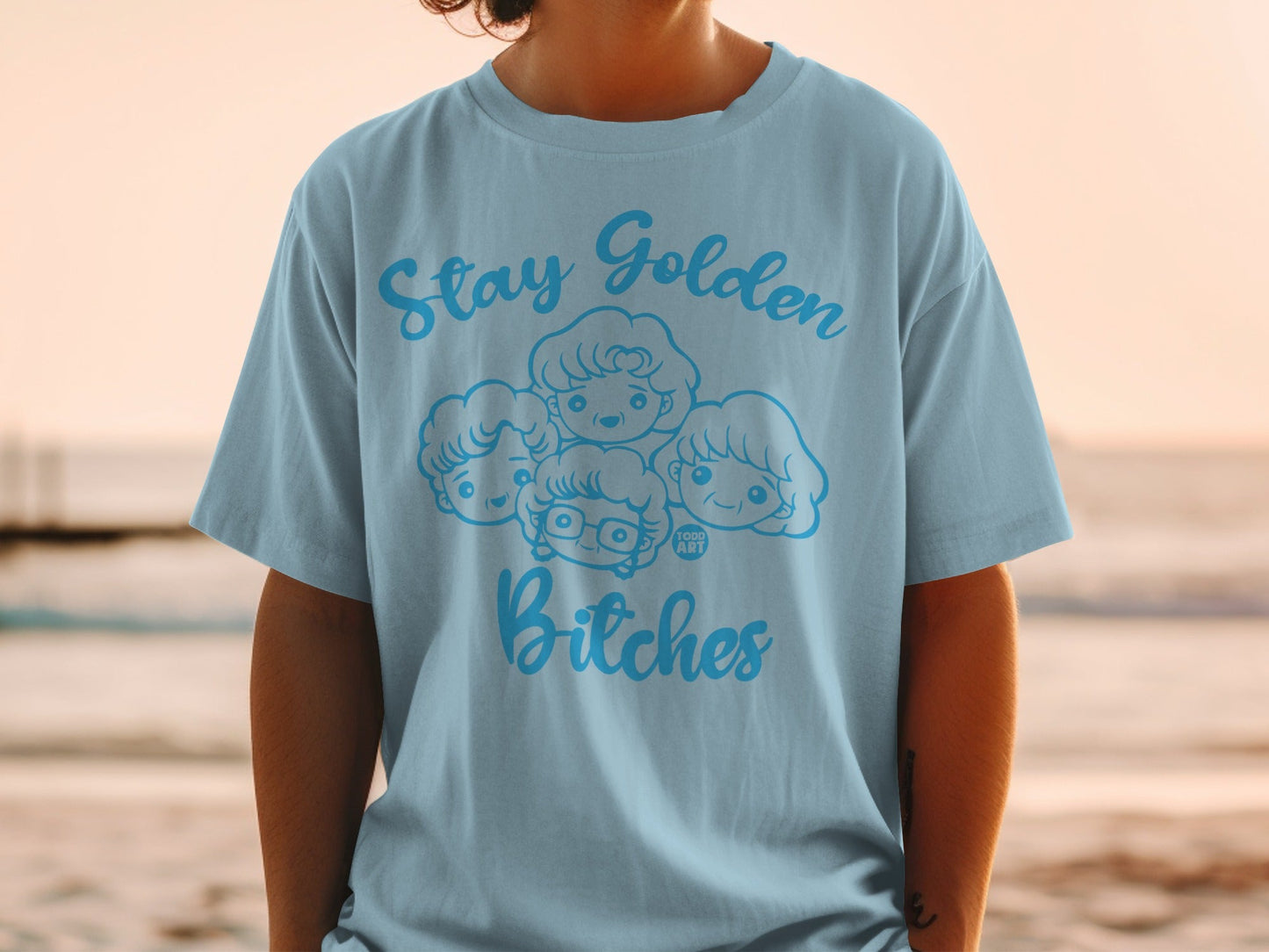 Light blue t-shirt with "Stay Golden Bitches" and cartoon portraits of four women.