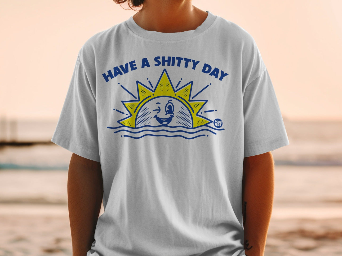 White t-shirt with sun graphic and text "HAVE A SHITTY DAY".