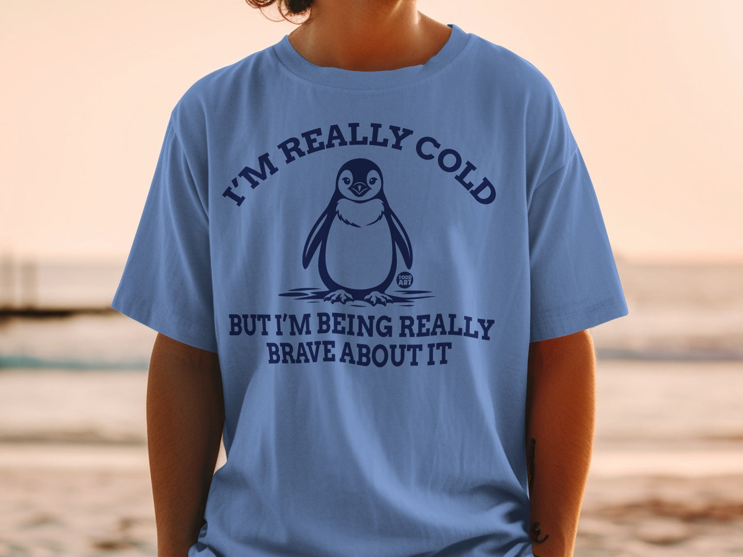 Blue t-shirt with penguin graphic and text "I'm really cold but I'm being really brave about it."