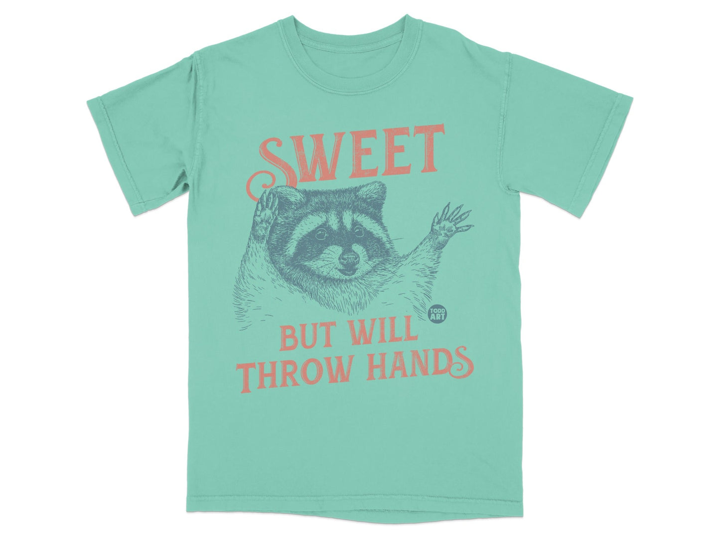 Teal t-shirt with raccoon graphic and text "SWEET BUT WILL THROW HANDS".