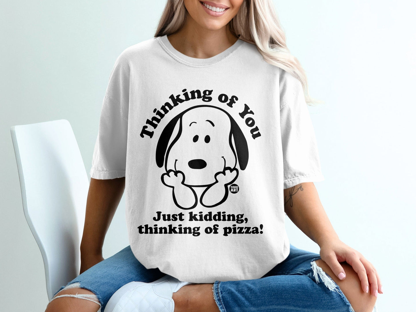 White t-shirt with Snoopy saying "Thinking of you. Just kidding, thinking of pizza!".