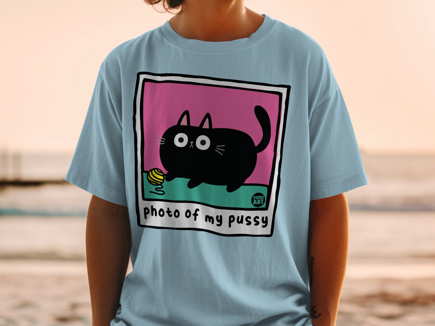 Light blue t-shirt featuring a cartoon black cat with big eyes playing with yarn.