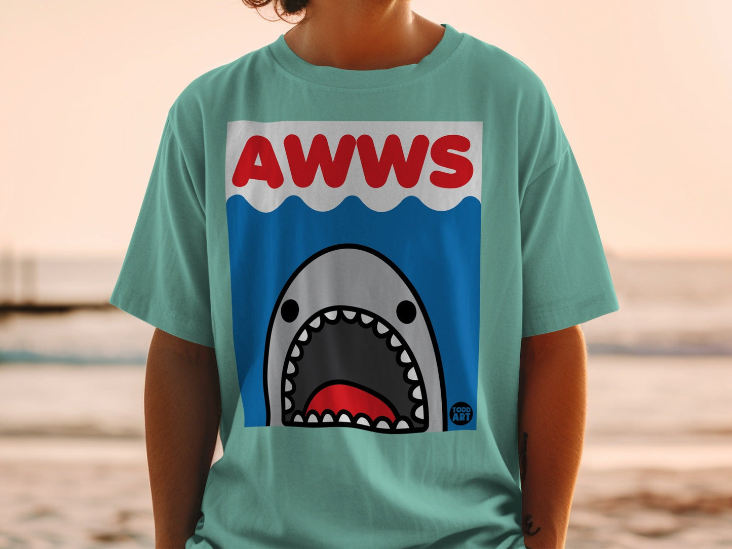 T-shirt with cartoon shark and "AWWS" text on blue water background.
