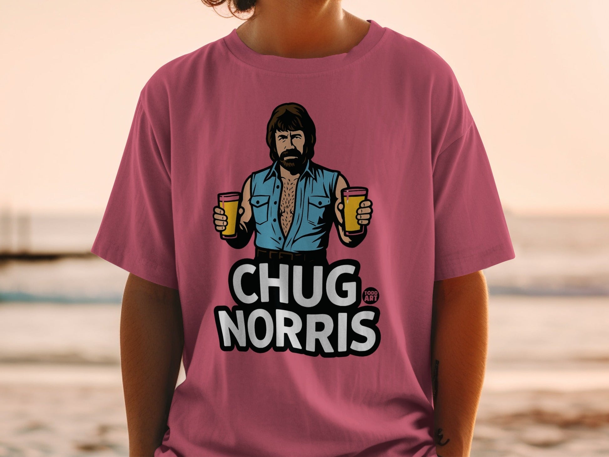 Pink t-shirt with illustration of Chuck Norris holding two beers.