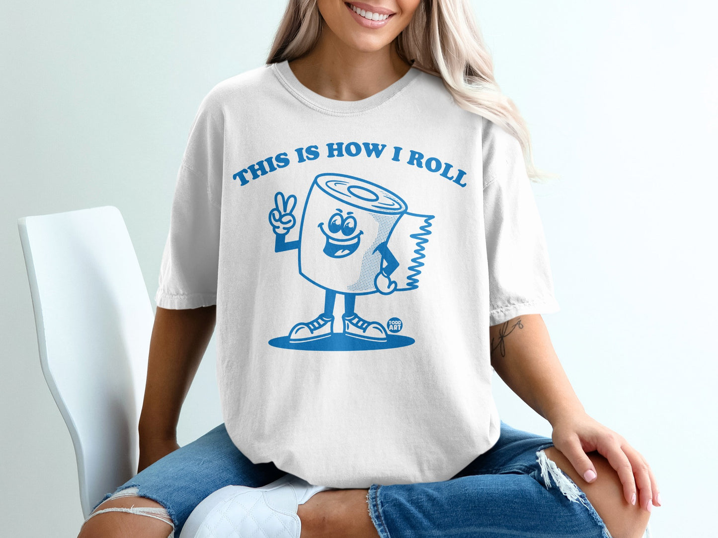 White t-shirt with blue cartoon toilet paper roll saying "This is how I roll."