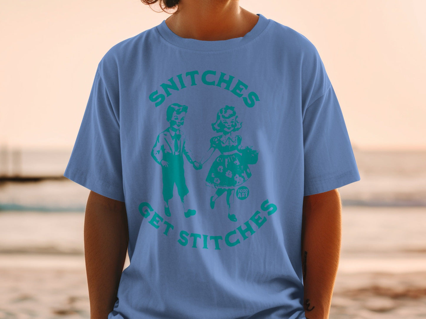 Blue t-shirt with "SNITCHES GET STITCHES" text and retro cartoon couple graphic.