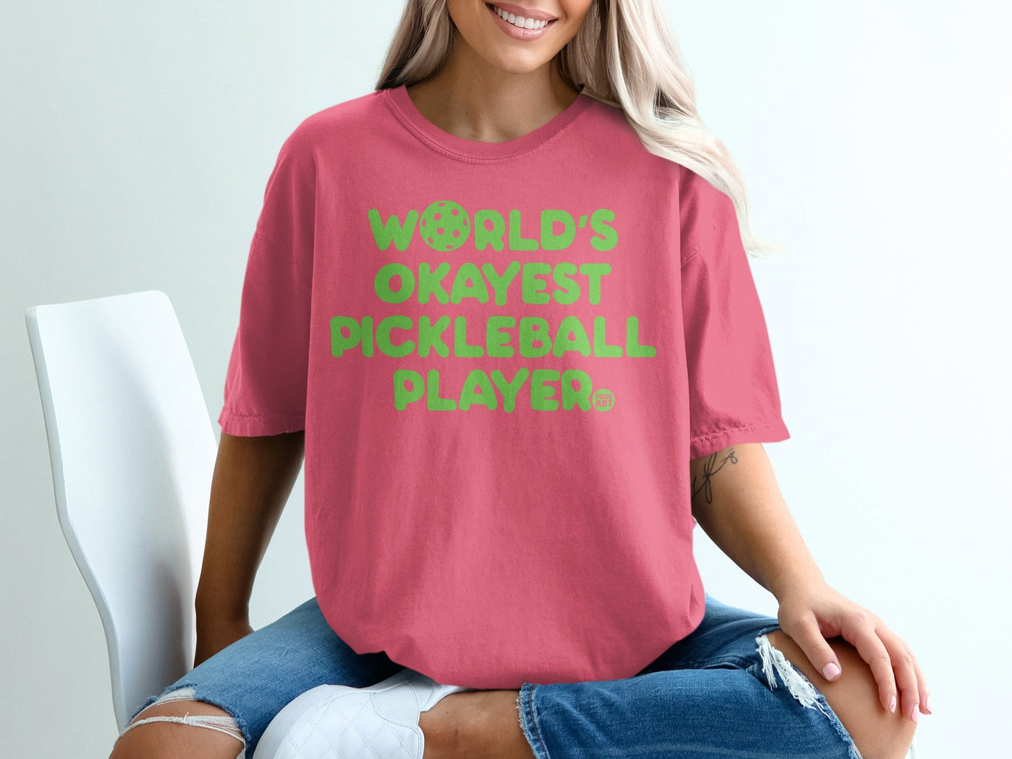 Pink t-shirt with "WORLD'S OKAYEST PICKLEBALL PLAYER" in green text.