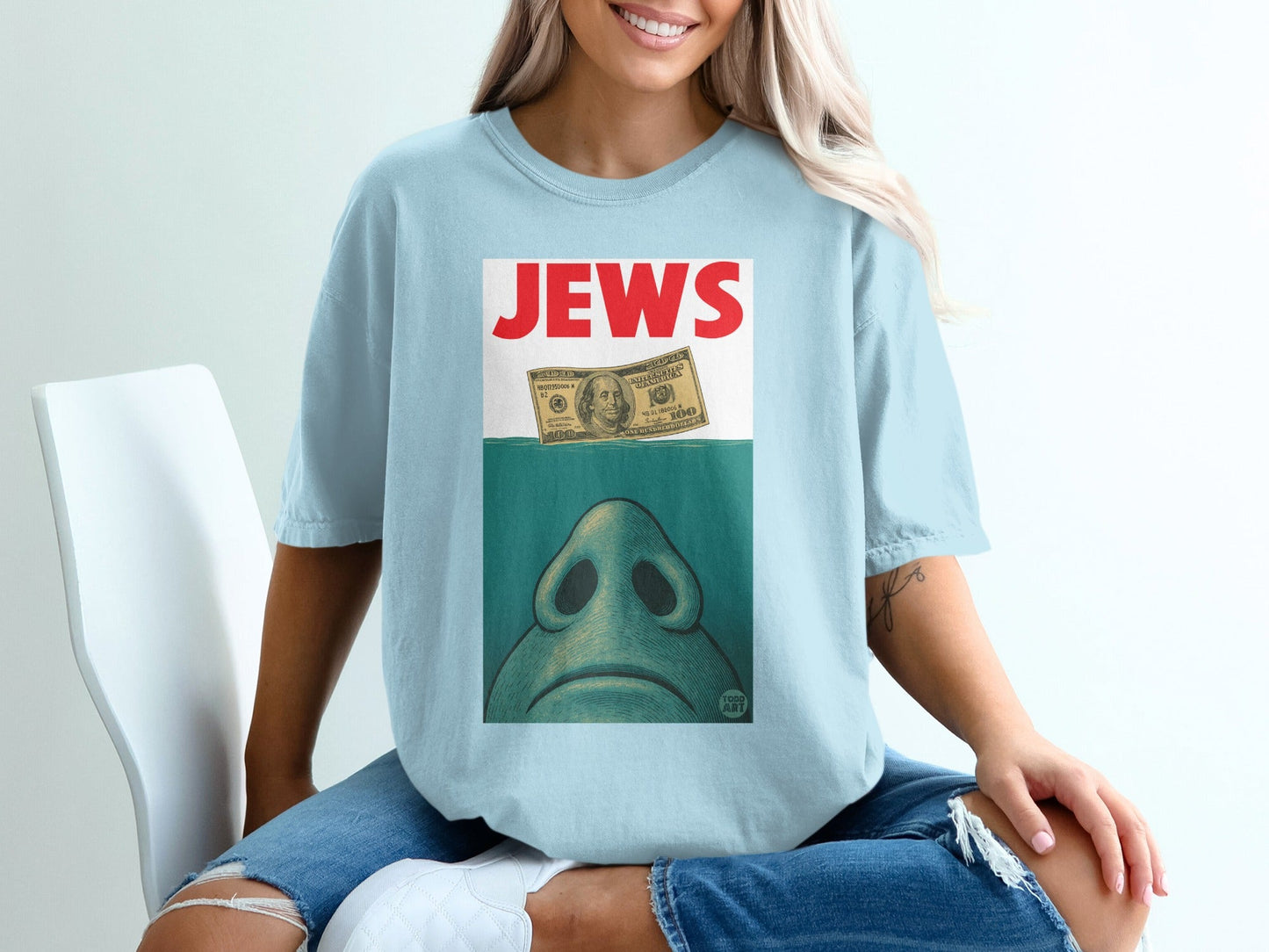 Light blue t-shirt with a stylized drawing of a nose above a hundred-dollar bill.