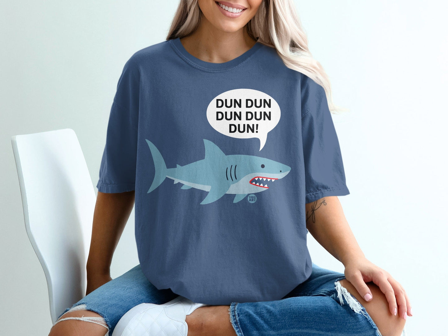 Shark wearing a shirt with "DUN DUN DUN DUN!" in a speech bubble.