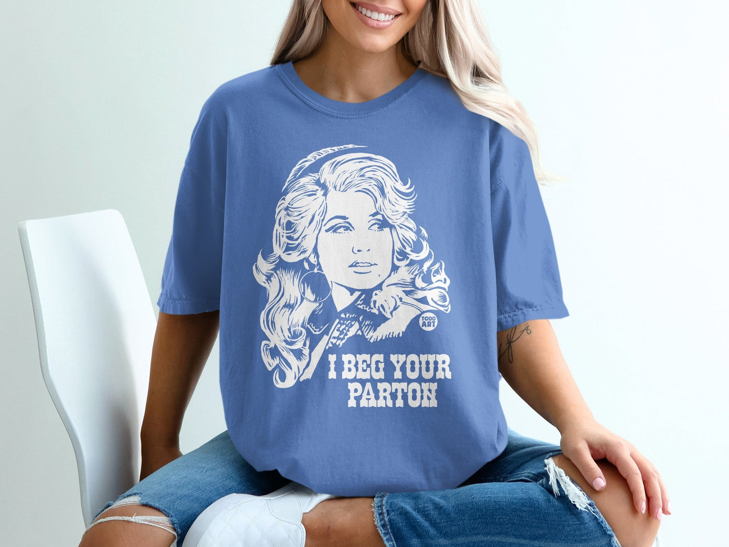 Blue t-shirt with Dolly Parton illustration and "I BEG YOUR PARTON" text.