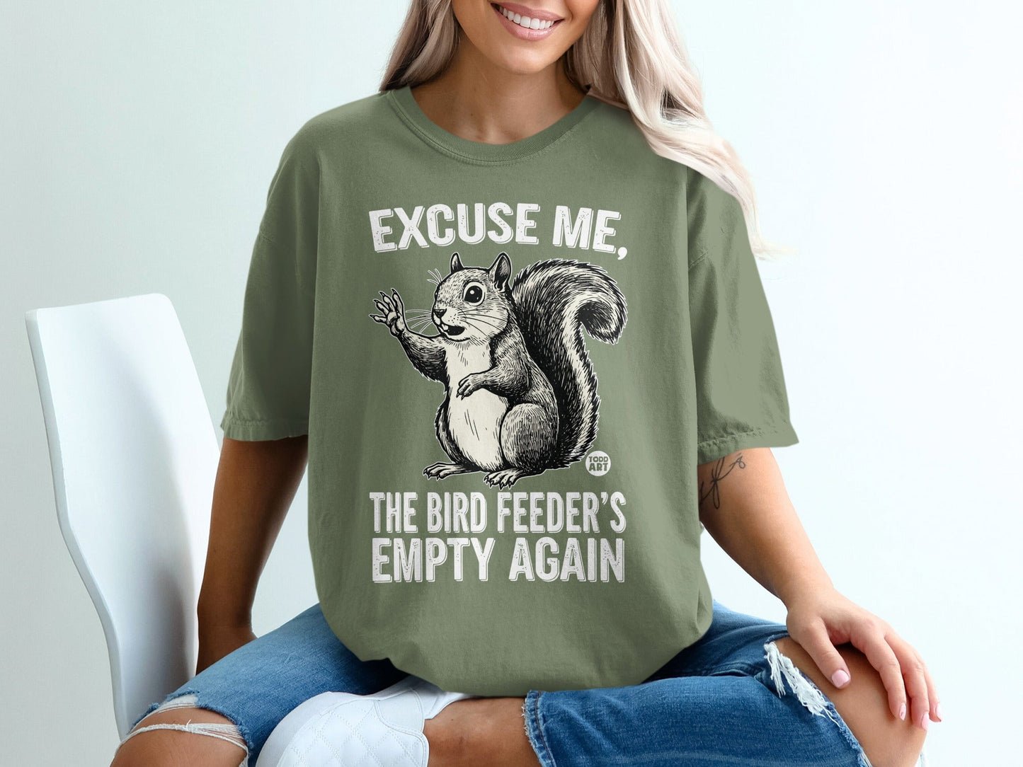 Green t-shirt with a squirrel graphic and text "Excuse me, the bird feeder's empty again".