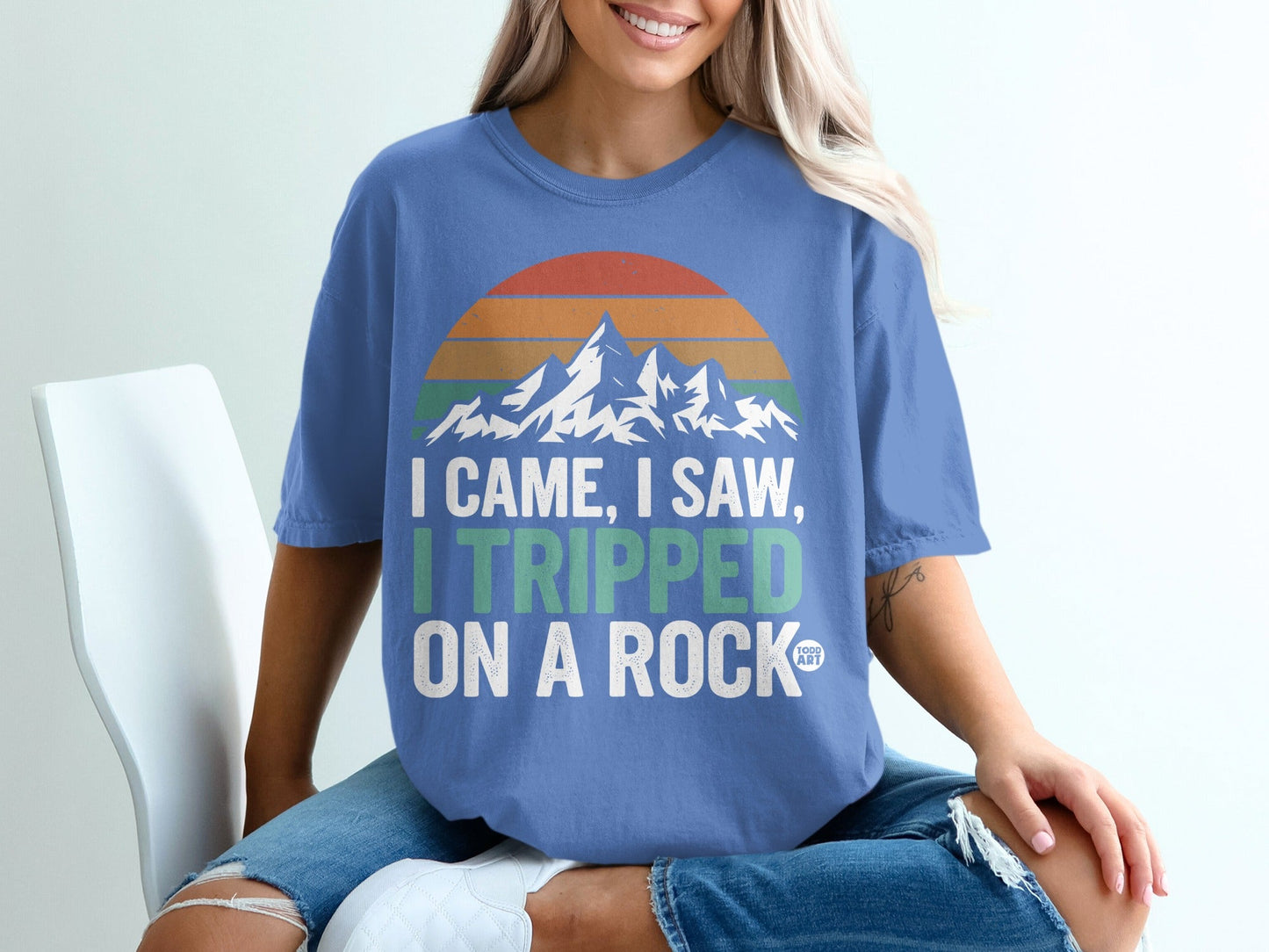 Blue t-shirt with mountains and text "I came, I saw, I tripped on a rock".