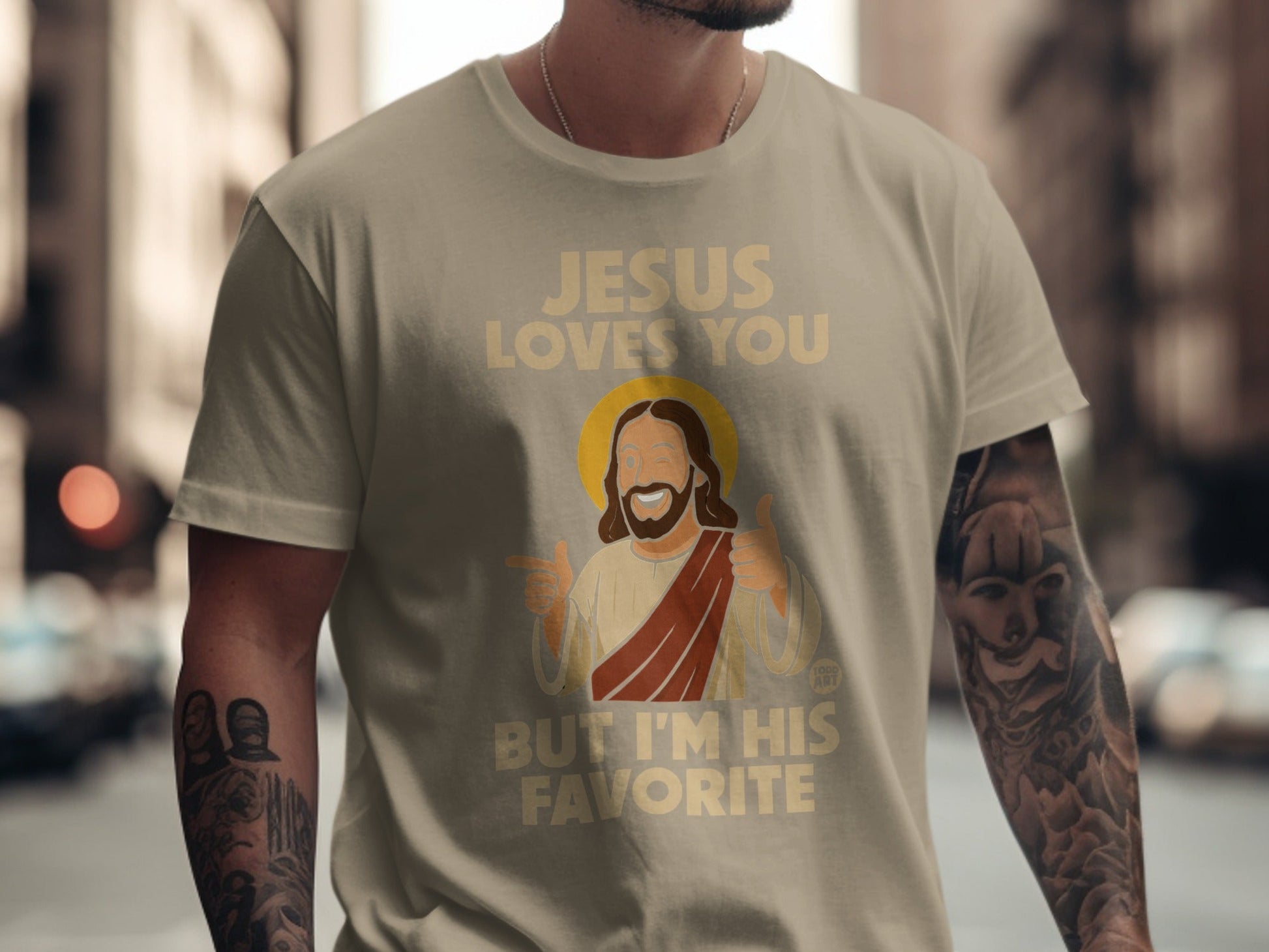Cream t-shirt with "Jesus Loves You But I'm His Favorite" text and cartoon Jesus.
