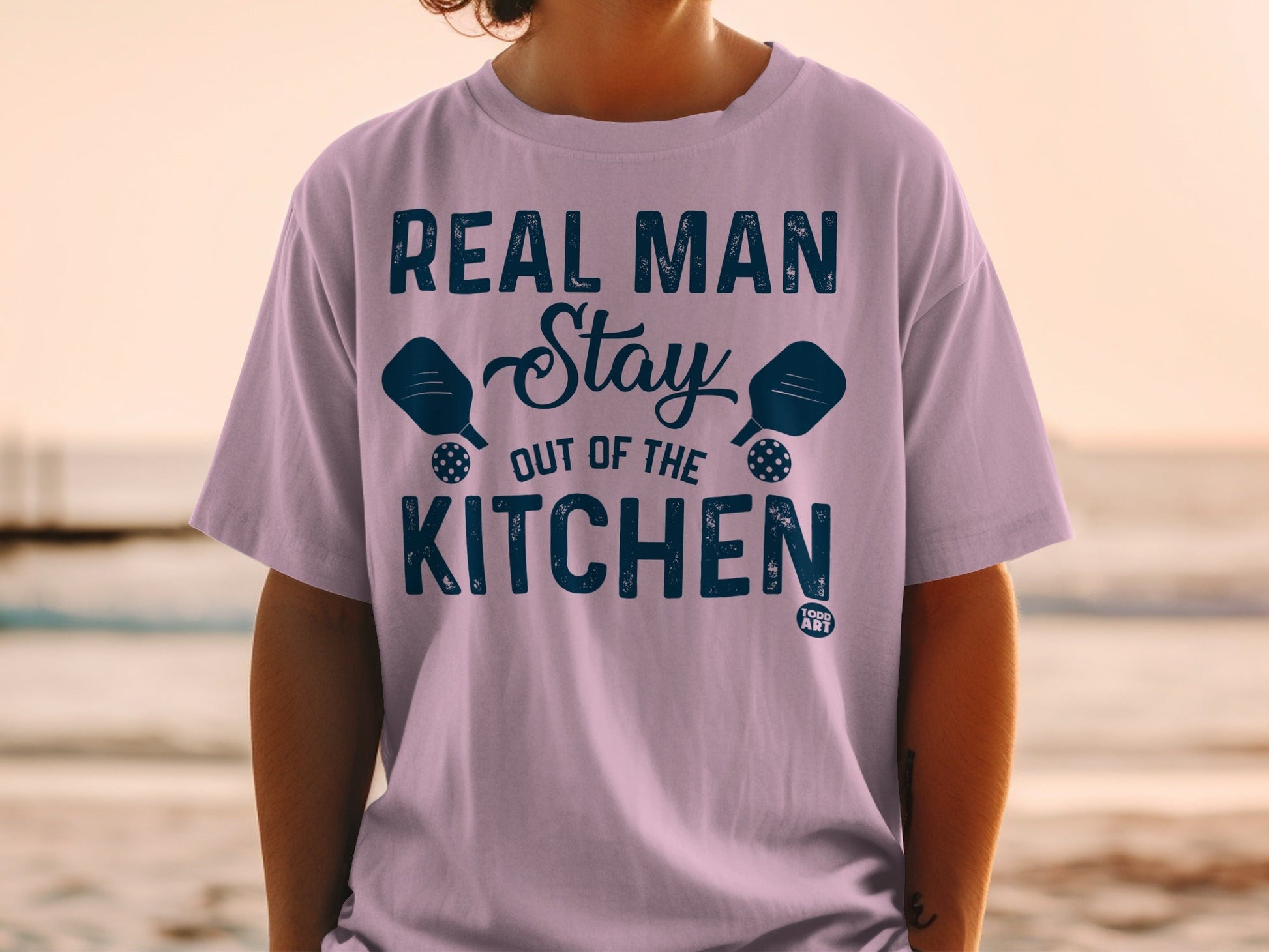 T-shirt with "Real Man Stay Out of the Kitchen" and pickleball paddles.