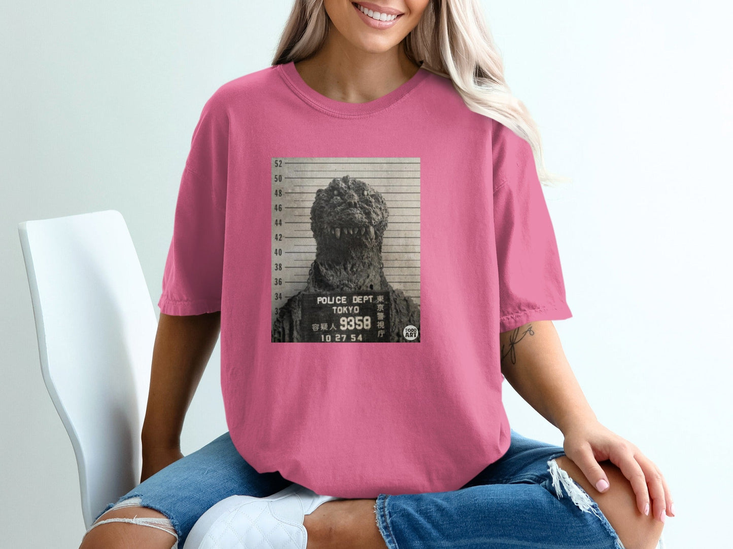 Pink t-shirt featuring a Godzilla mugshot with "POLICE DEPT TOKYO" text.