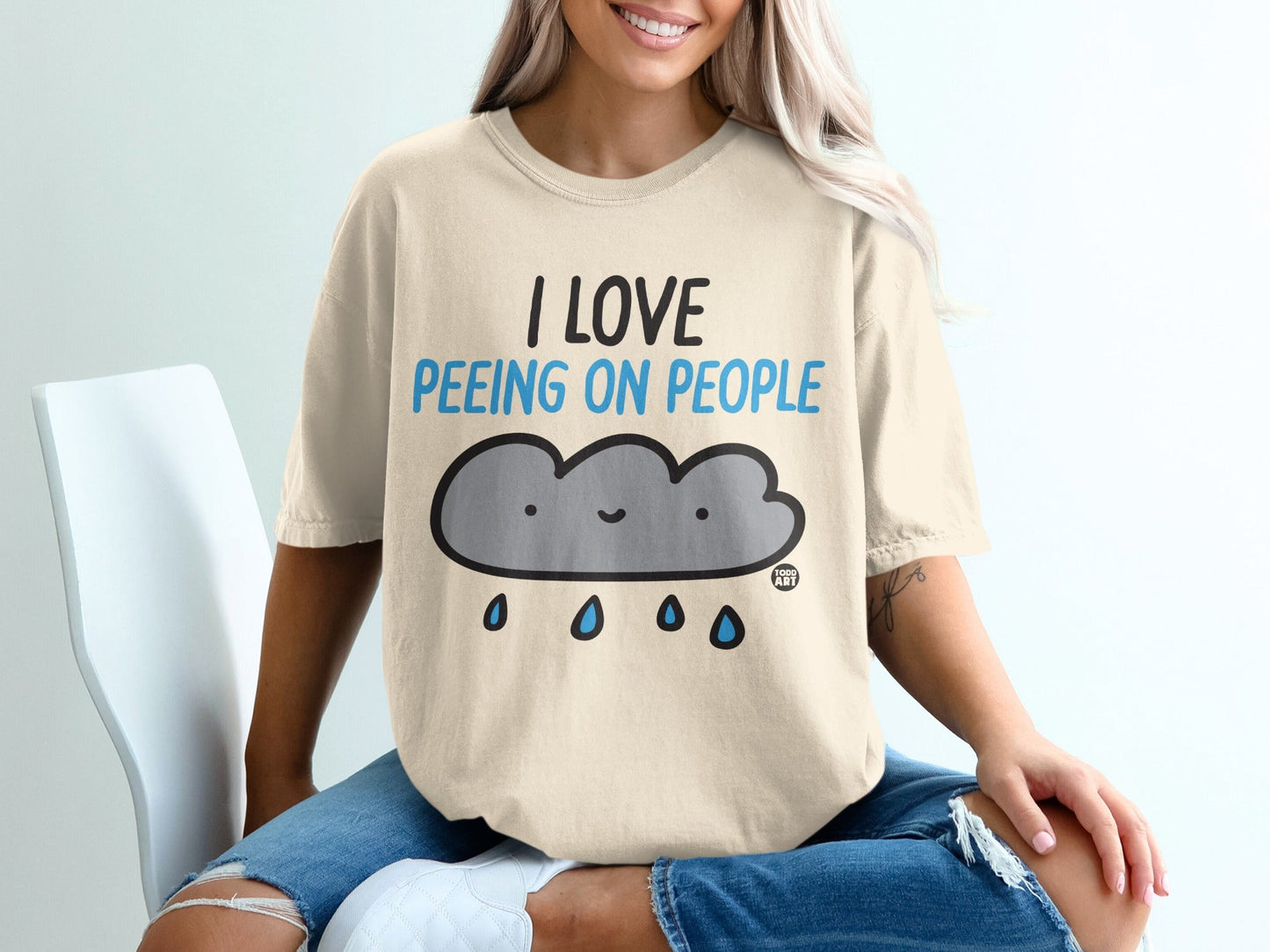 Cream t-shirt with a smiling cloud graphic and "I LOVE PEEING ON PEOPLE" text.