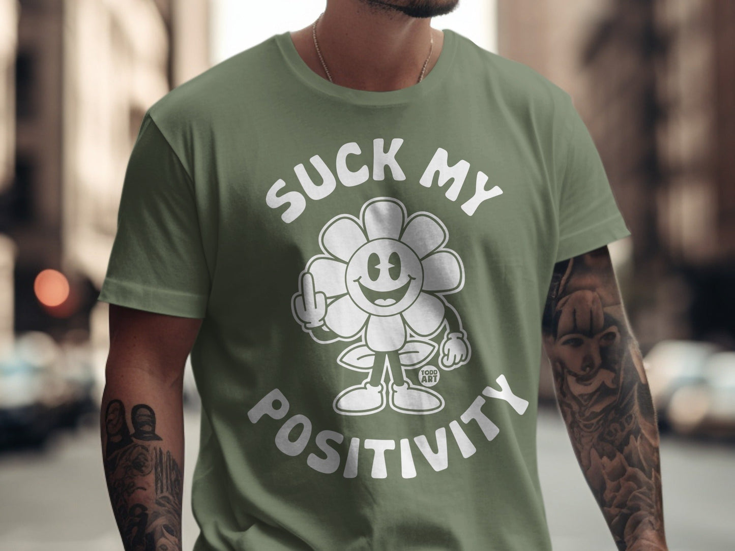 Green t-shirt with a cartoon flower giving middle finger saying "SUCK MY POSITIVITY".