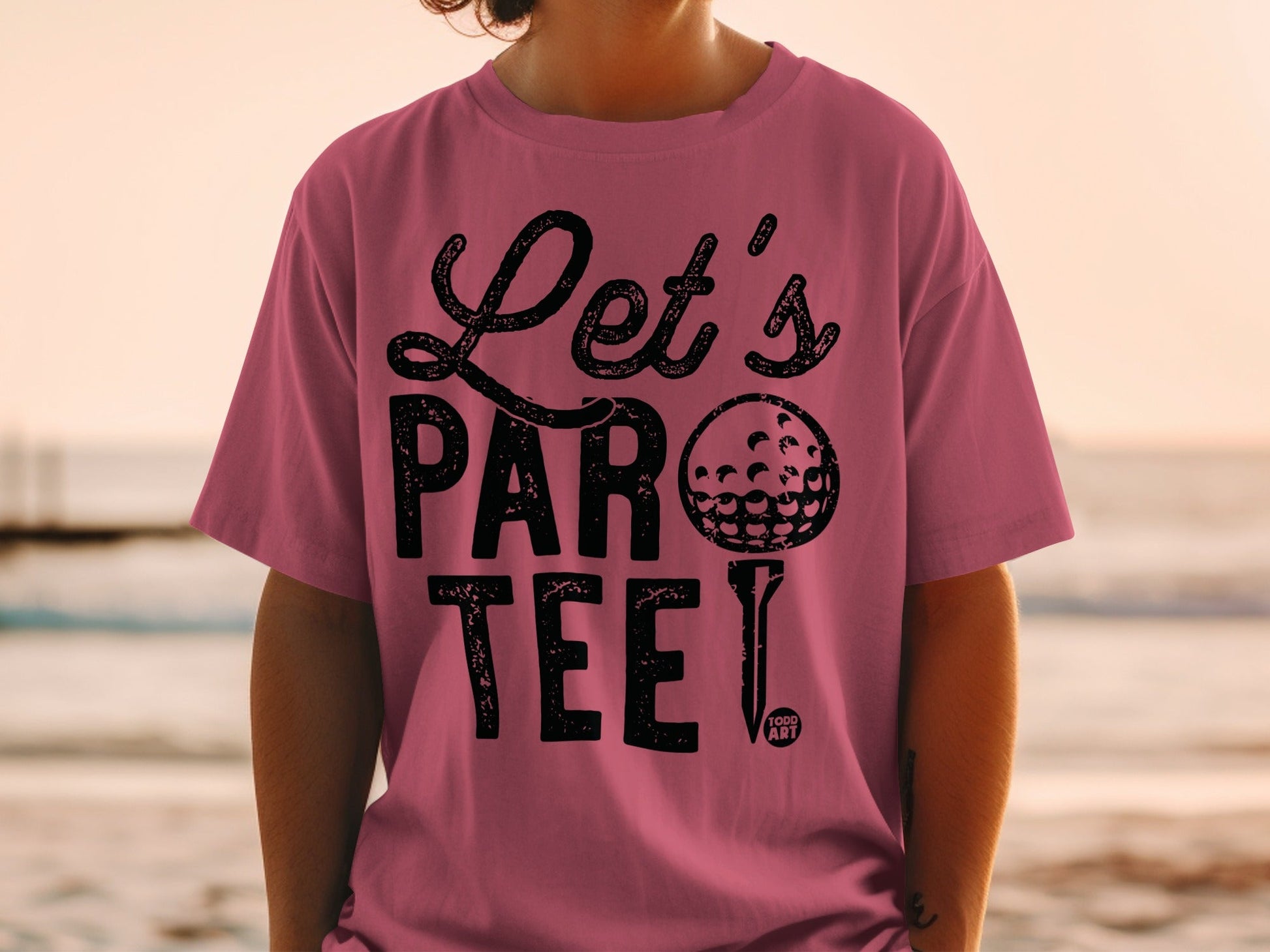 Pink t-shirt with "Let's Par Tee!" text and golf ball graphic.