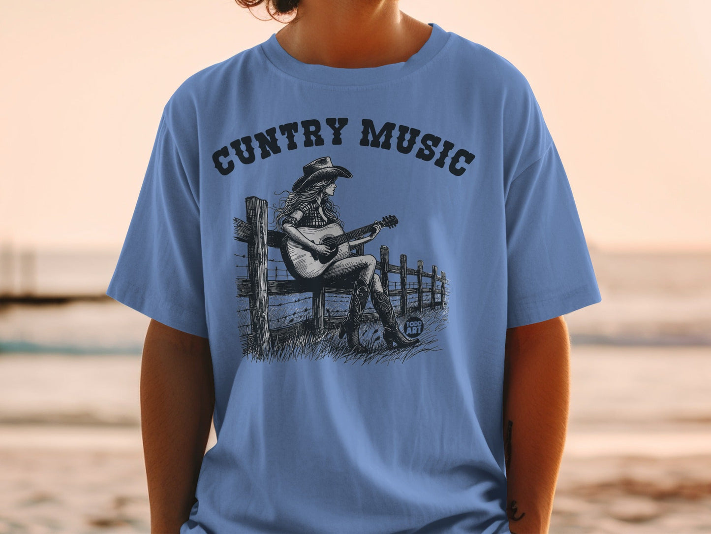 Graphic tee with country music text and woman playing guitar on fence.