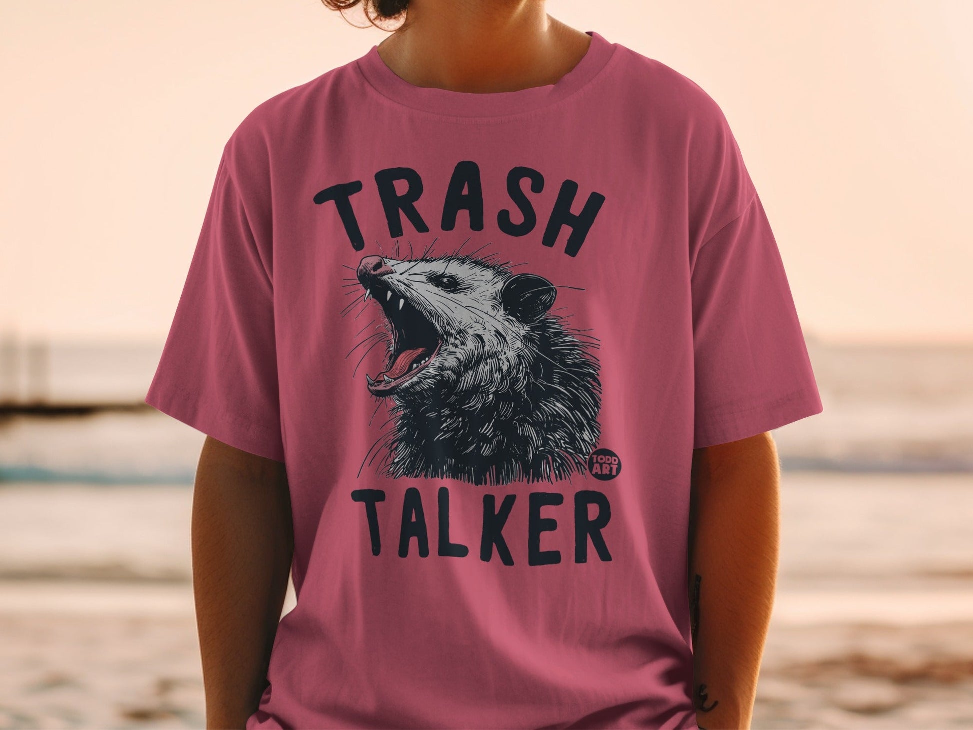 Pink t-shirt with "TRASH TALKER" and a snarling opossum graphic.