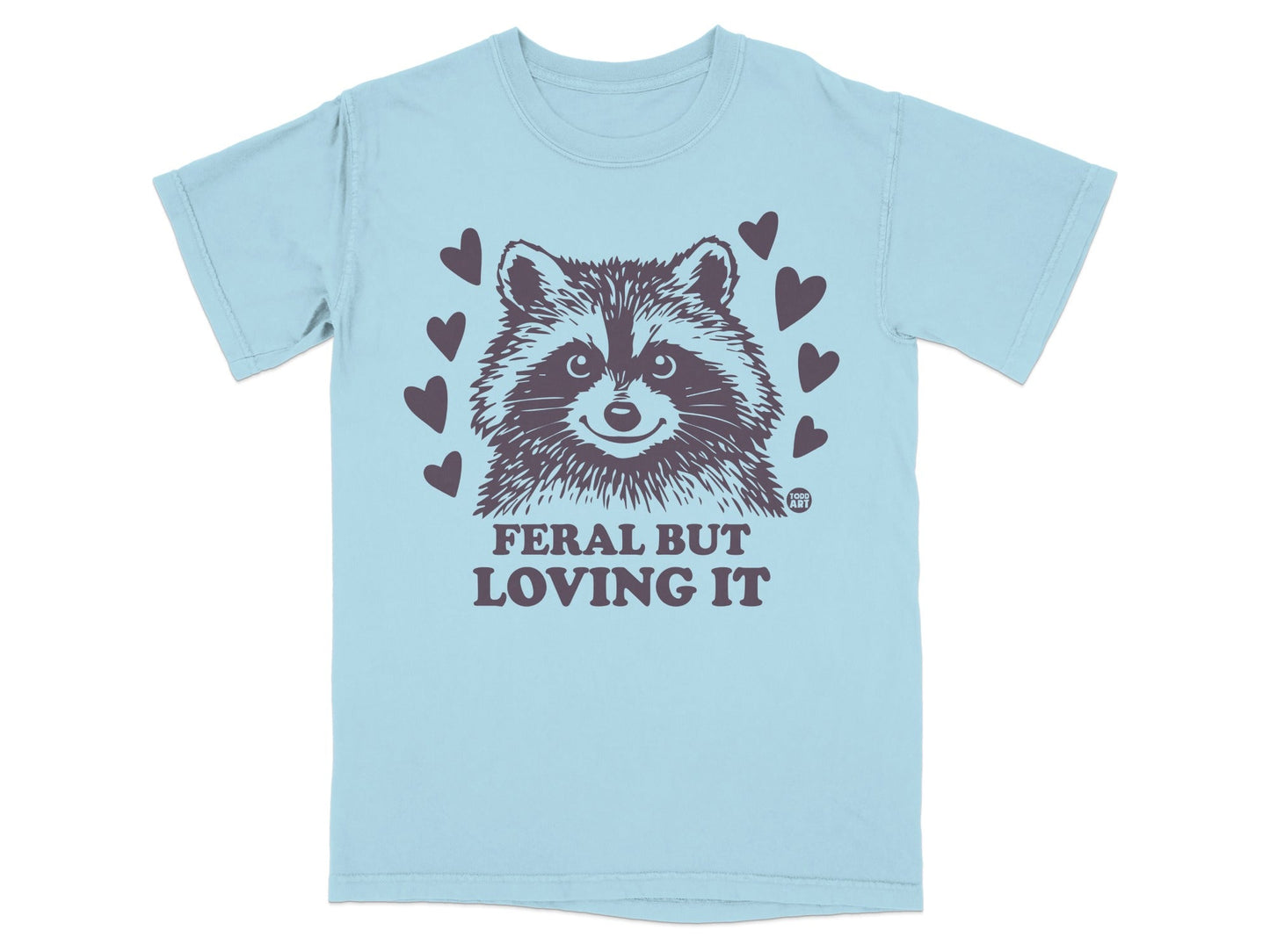 Light blue t-shirt with raccoon and "FERAL BUT LOVING IT" text.