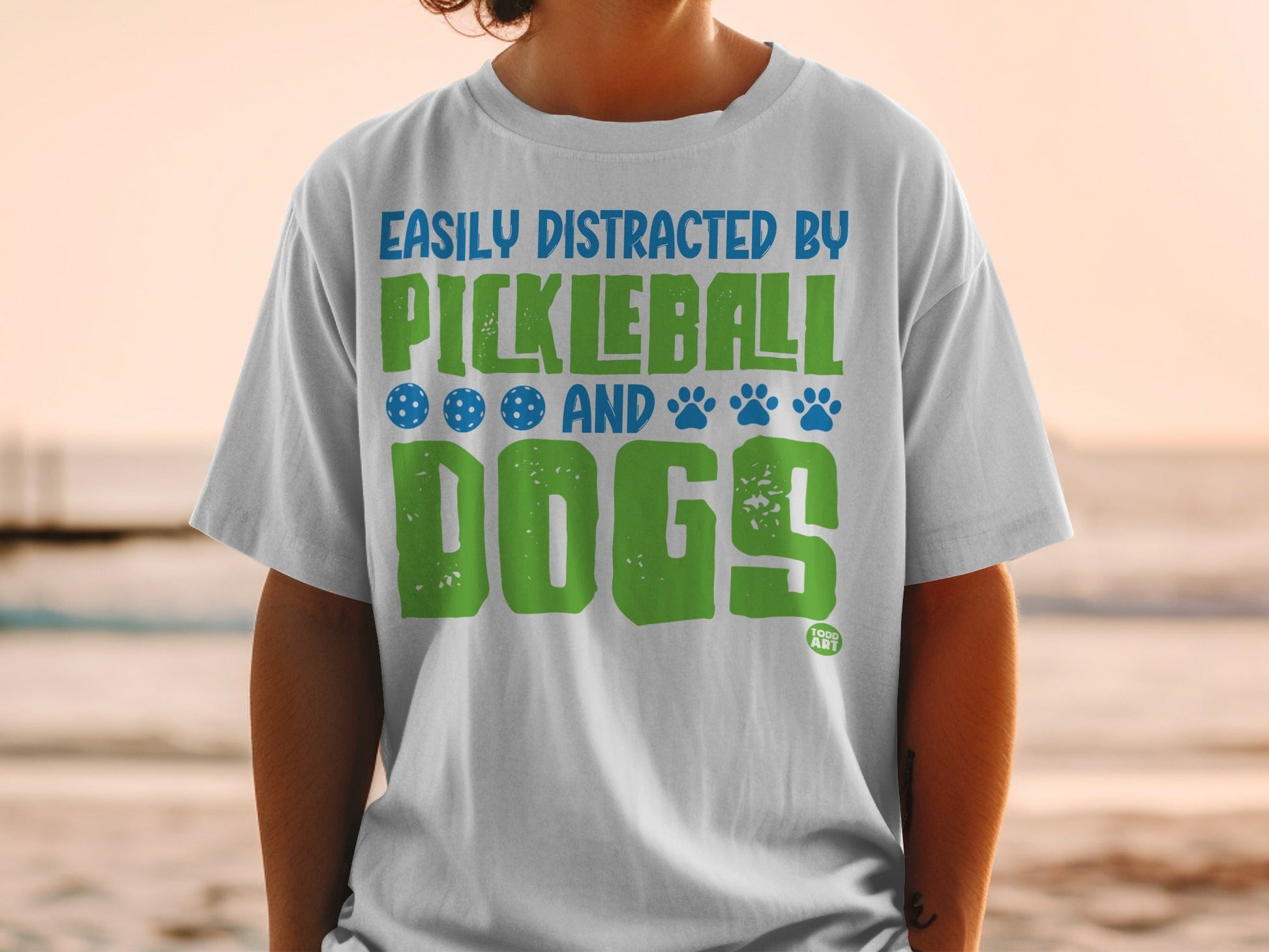 White t-shirt with "Easily Distracted by Pickleball and Dogs" text and graphics.
