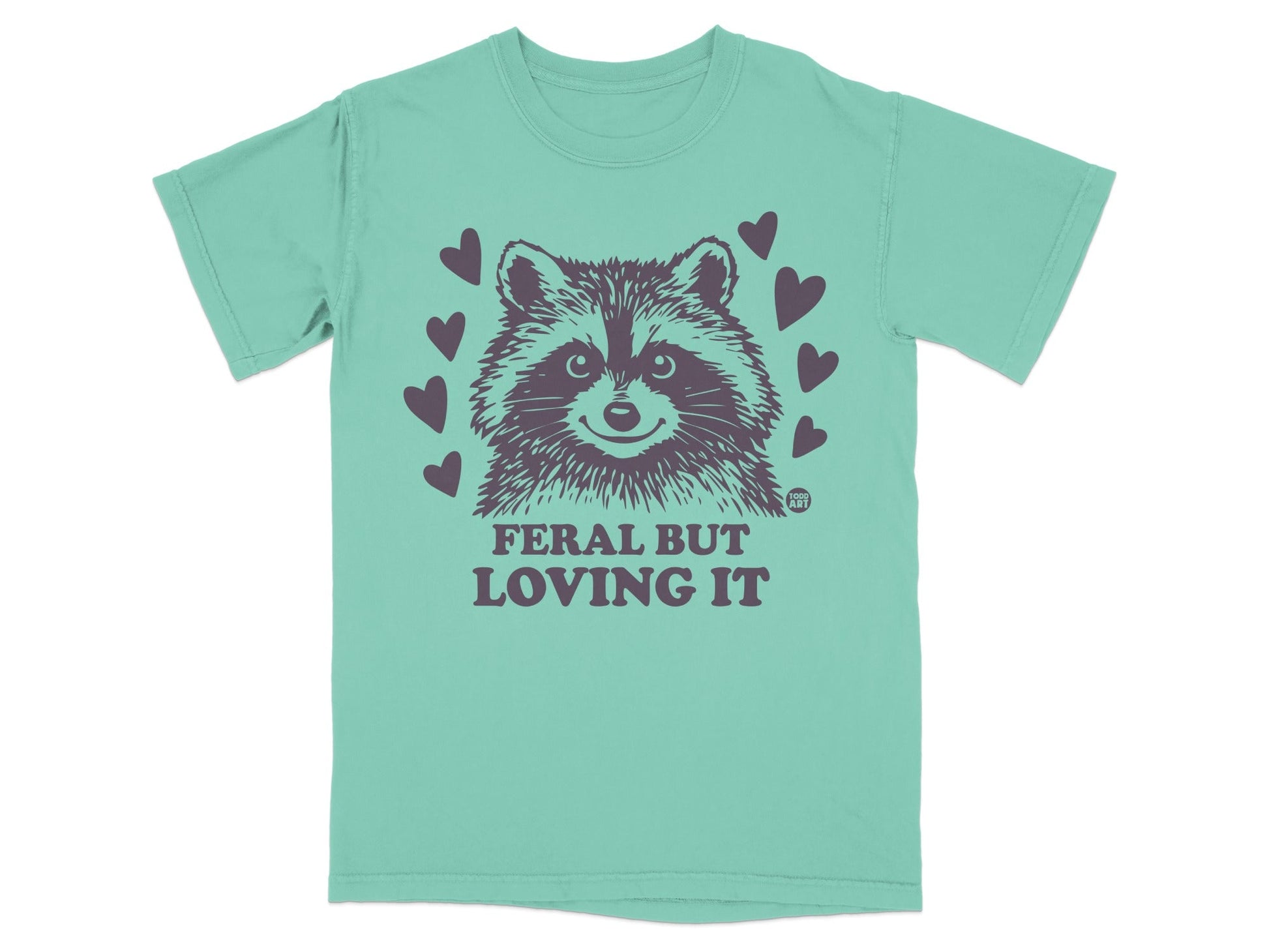 Teal t-shirt with raccoon graphic and text "FERAL BUT LOVING IT".