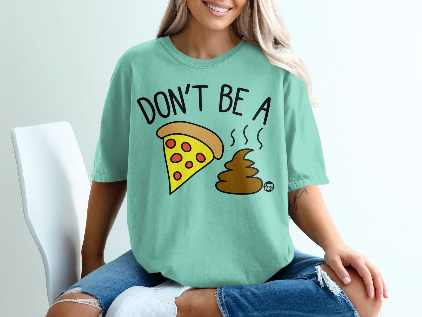 Mint t-shirt with "Don't Be A Shit" text and pizza slice with poop emoji.