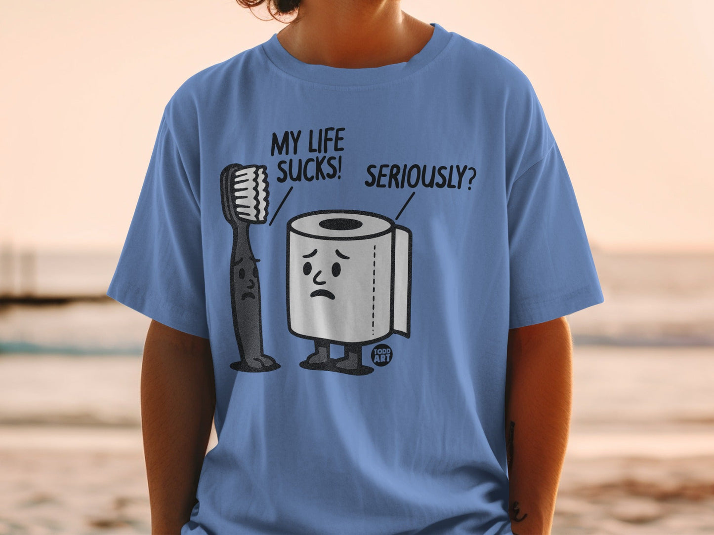 Blue t-shirt with sad toothbrush and toilet paper characters on it.
