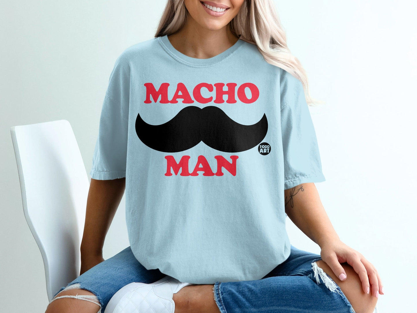 Light blue t-shirt with "MACHO MAN" and a black mustache graphic.