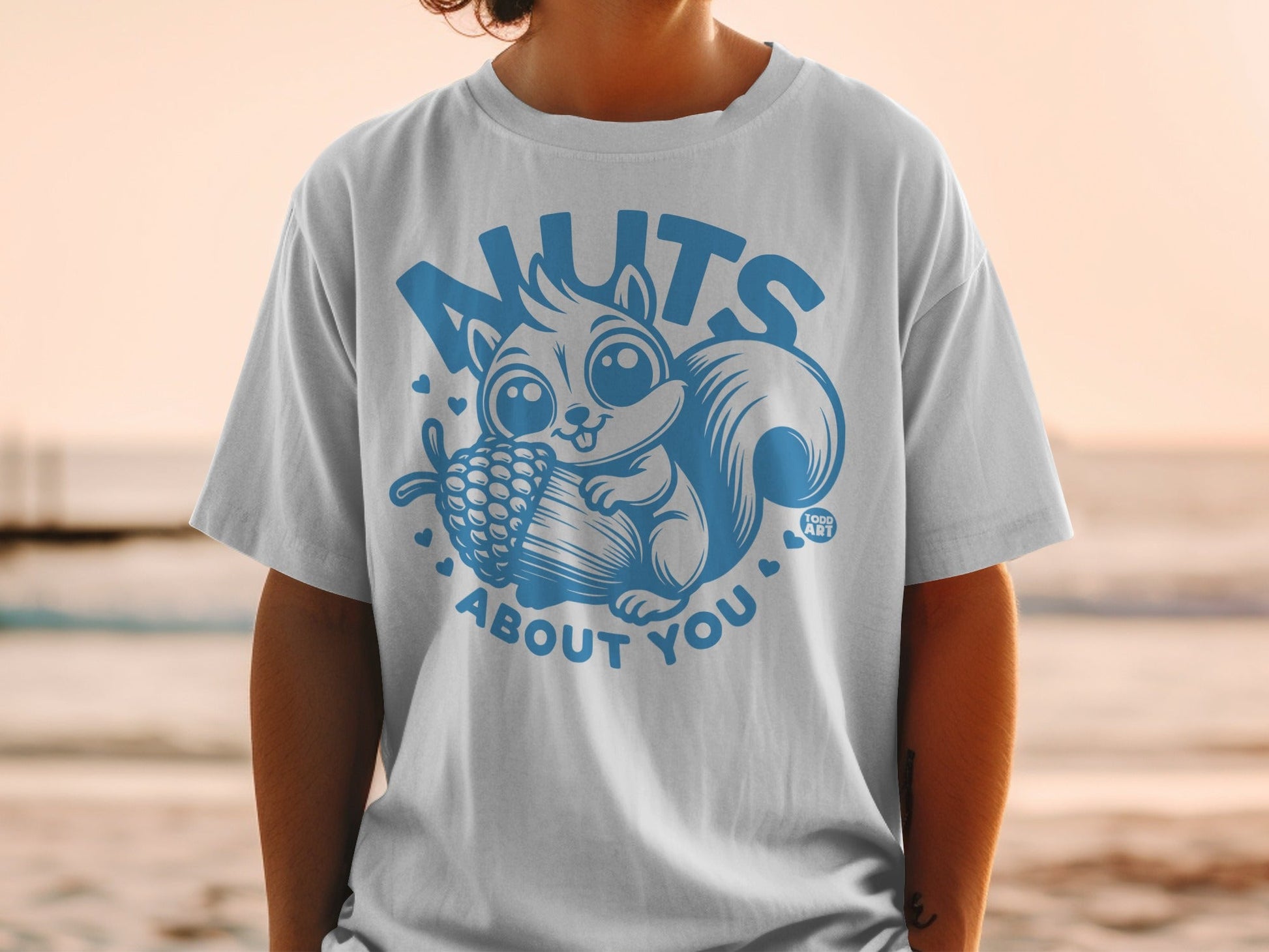 Blue graphic t-shirt with a cartoon squirrel holding a pinecone and text "NUTS ABOUT YOU".