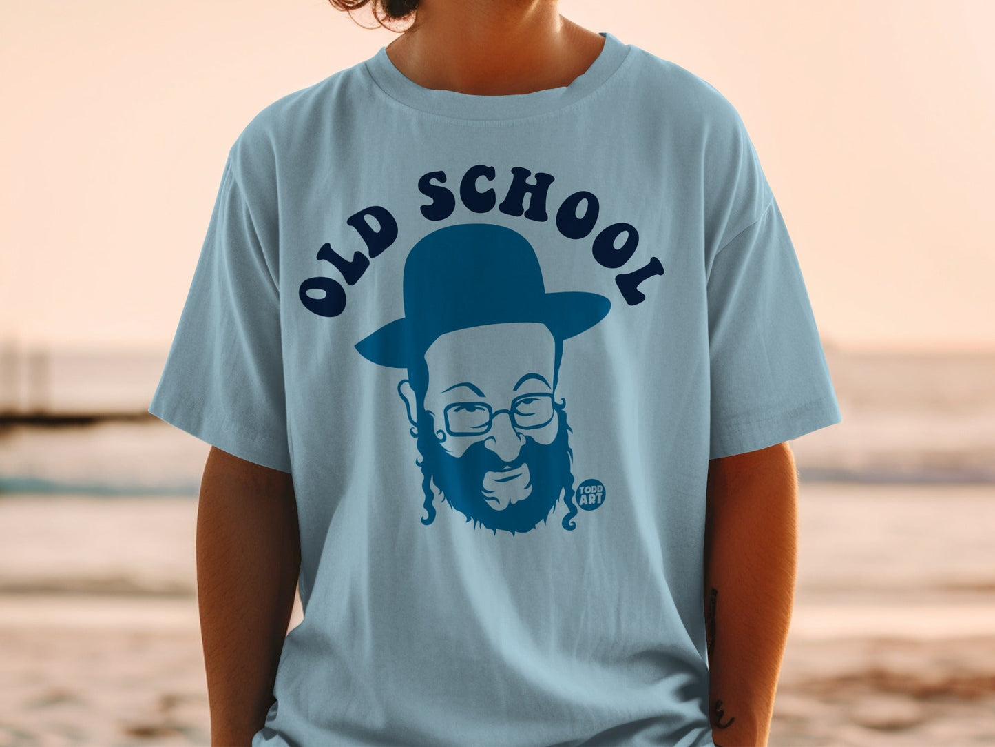 Light blue t-shirt featuring a cartoon portrait with beard, glasses, and hat.