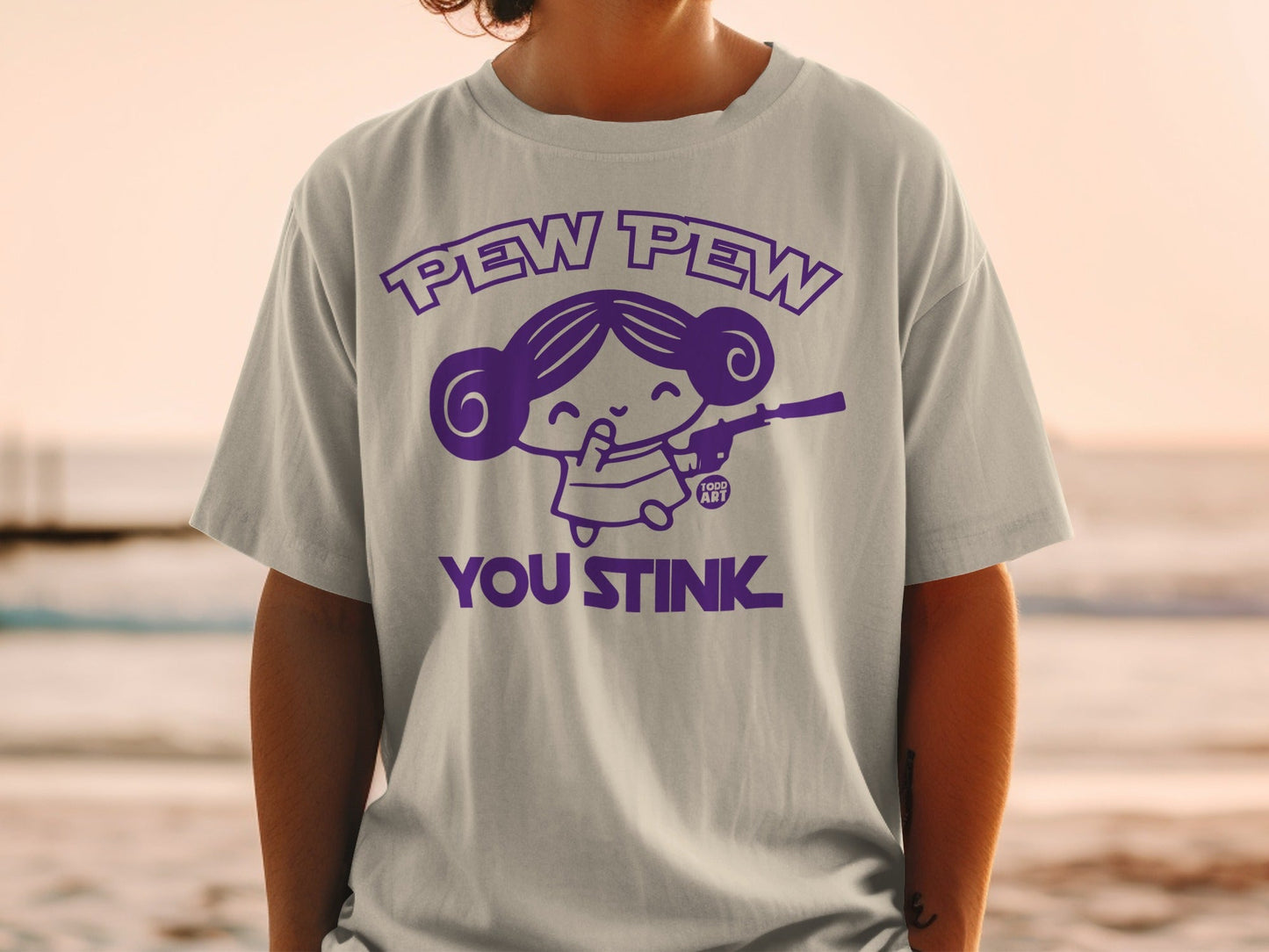 T-shirt with "Pew Pew You Stink" graphic of a girl with a gun.