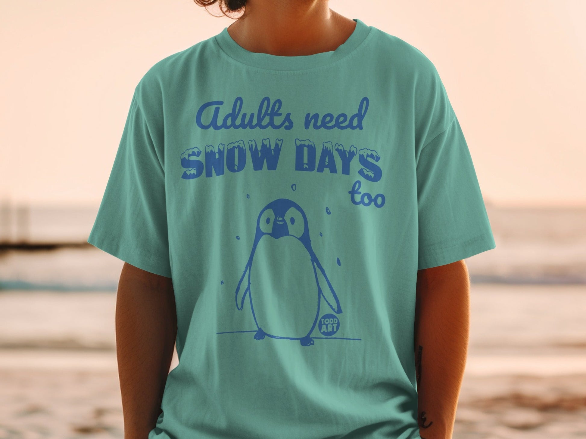 T-shirt with text "Adults need SNOW DAYS too" and a penguin graphic.